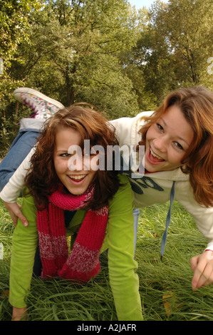 Due sorelle adolescenti allegramente scorazzare in erba Foto Stock