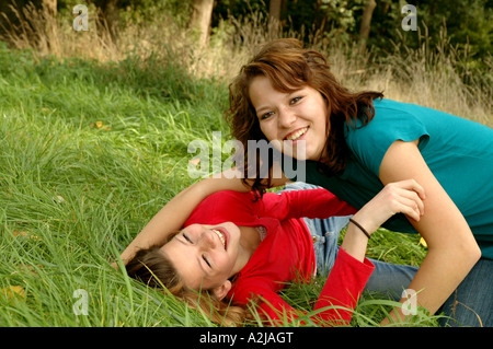 Due sorelle adolescenti allegramente scorazzare in erba Foto Stock