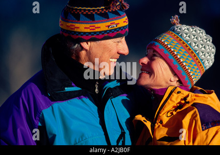 Una coppia matura sguardo in ogni altri occhi all'aperto in un luogo fresco ma giornata di sole Foto Stock