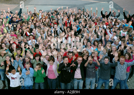 Grande gruppo di i bambini della scuola secondaria cercando e agitando la fotocamera A Foto Stock