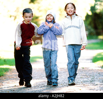 Tre bambini a piedi nei boschi casual da indossare vestiti a piedi e divertirsi. Vi età è 6-8, ci sono 2 ragazze e 1 ragazzo Foto Stock
