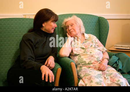 Donna di mezza età/figlia/lavoratore di cura la visita molto vecchia signora/la madre nella casa di cura Foto Stock