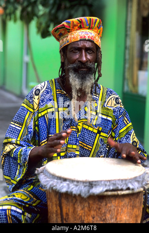 Colorato Rasta reggae giamaicano attore sul tamburo in costume al porto di St John Antigua Foto Stock