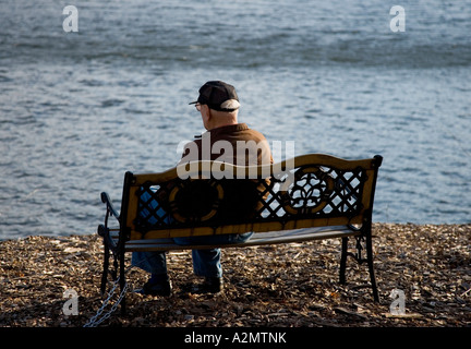 Uomo anziano seduto su una panchina Foto Stock