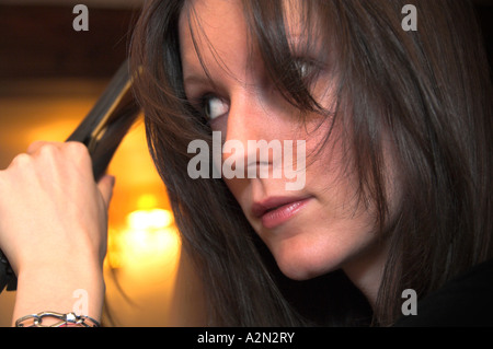 La donna la raddrizzatura i suoi capelli Foto Stock