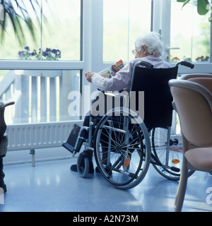 Senior donna seduta in carrozzella Foto Stock