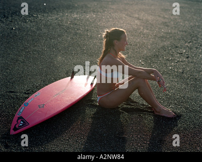 Surfer Sarah Bentley seduta con scheda sulla spiaggia, Isole Canarie, Spagna Foto Stock