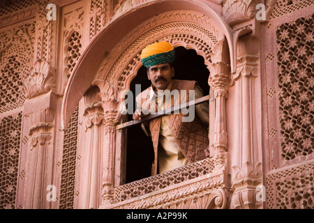 India Rajasthan Jodhpur Fort Meherangarh turbanned uomo guardando fuori riccamente intagliato finestra Foto Stock