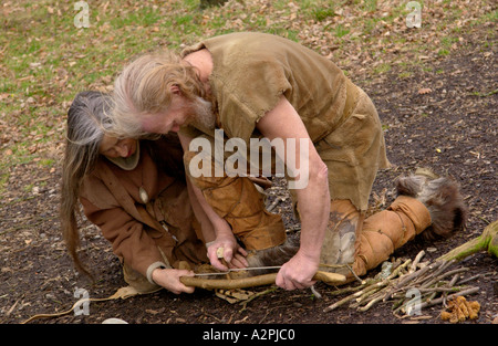 L'uomo preistorico & donna età della pietra reenactors cercando di dare fuoco al Museum of Welsh Life St Fagans Cardiff Wales UK Foto Stock