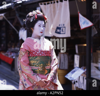 La ragazza di maiko partecipante Geisha costume passeggiando per le strade di Kyoto Gion indossare il kimono obi parrucca parasol trucco rossetto Foto Stock