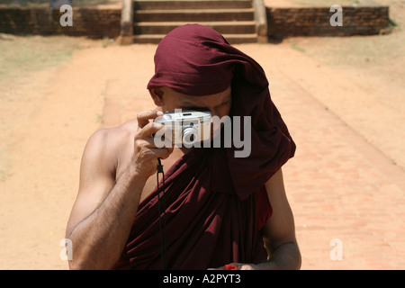 Sri Lanka, un monaco vestito di vesti maroon scatta una fotografia di una famosa Pietra di luna a Mahasen's Palace, Anuradhapura Foto Stock