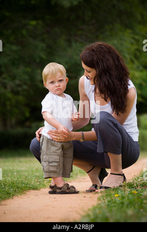 Madre caucasica comfort giovane maschio bambino in park land impostazione Foto Stock