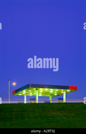 La stazione di benzina al crepuscolo con luci luminose e cielo blu Foto Stock