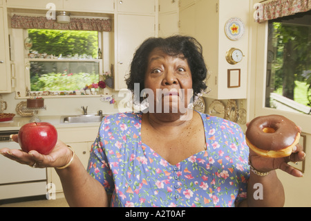 Donna di decidere tra una mela o una ciambella Foto Stock