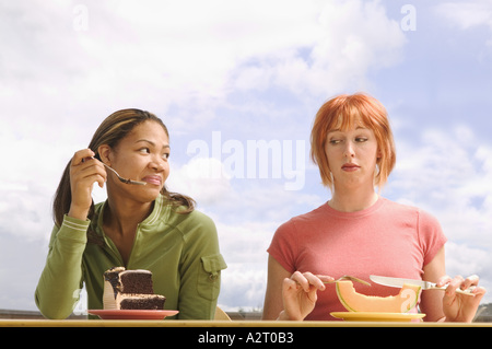 Due donna mangiare molto diversi di cibo Foto Stock