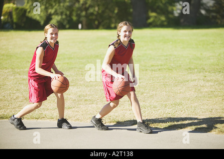 Twin teen ragazze dribbling basketballs Foto Stock