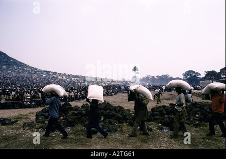 Rifugiati ruandesi luglio 1994 folla di persone che aspettano gli uomini che trasportano i sacchi di aiuti sulle loro teste a croce rossa della distribuzione alimentare centro kibumba nel campo di rifugiati di Goma Foto Stock