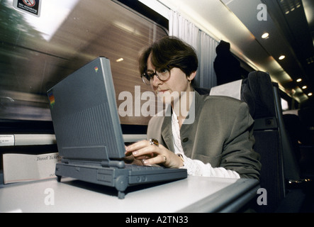 Donna che utilizza sul computer portatile sul treno 1992 Foto Stock