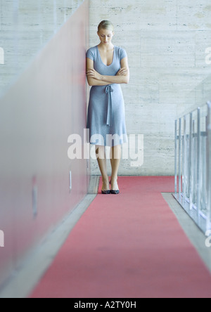 Donna in piedi appoggiata contro la parete, a testa in giù a piena lunghezza ritratto Foto Stock