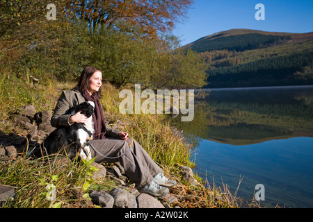 Donna seduta con il cane in autunno, west calder serbatoio, Brecon Beacons NP, Galles GB Foto Stock