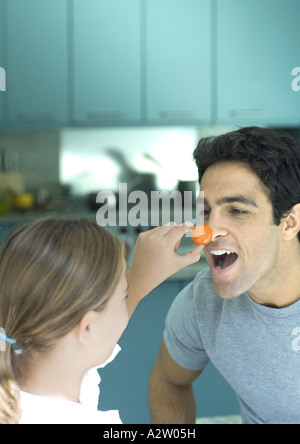 Ragazza con fino pomodoro ciliegino all uomo del naso Foto Stock