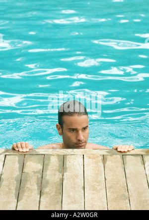 Uomo in piedi in piscina con le mani sul bordo Foto Stock
