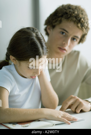 Ragazzo adolescente aiutando sorella più giovane con i compiti Foto Stock