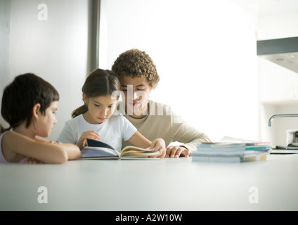 Ragazzo adolescente aiutando sorella più giovane con i compiti Foto Stock