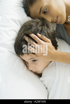 Bambino che giace nel letto con la madre Foto Stock