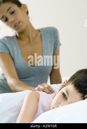 Bambino giacente in letto, madre guardando Foto Stock