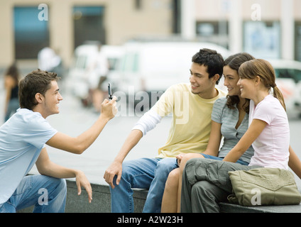 Ragazzo adolescente prendendo foto di amici con un telefono cellulare Foto Stock