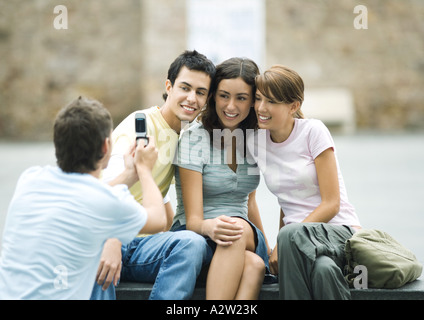 Ragazzo adolescente prendendo foto di amici con un telefono cellulare Foto Stock