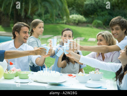La famiglia bicchieri tintinnanti sulla torta di compleanno Foto Stock