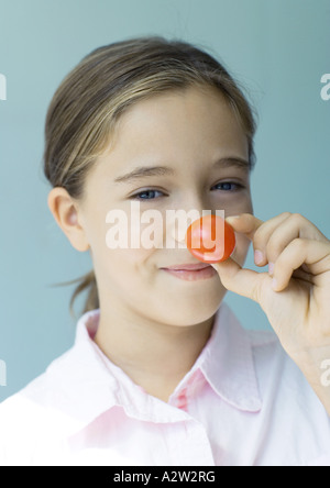 Ragazza con fino pomodoro ciliegino a naso Foto Stock