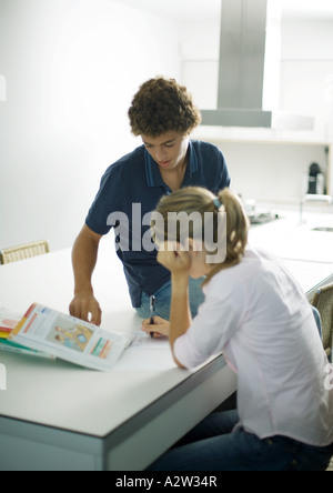 Ragazzo adolescente aiutando la sorella con i compiti Foto Stock