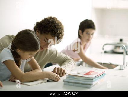 Ragazzo adolescente aiutando la sorella con i compiti Foto Stock