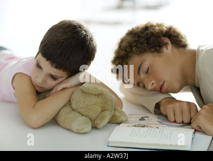 Ragazzo adolescente e giovane gemelli di addormentarsi durante la lettura del libro Foto Stock