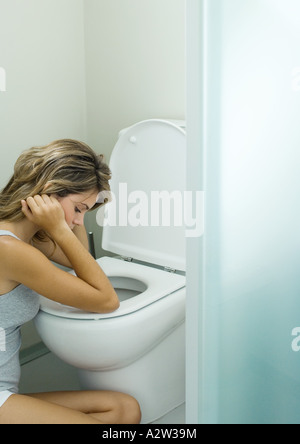 Giovane donna seduta accanto alla toilette Foto Stock