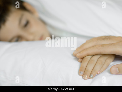 Bambino giacente in letto, genitore in possesso di mano Foto Stock