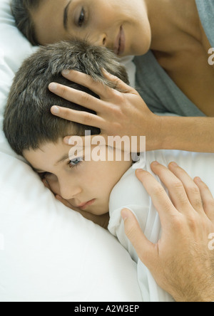 Bambino giacente nel letto dei genitori le mani sulla testa e la spalla Foto Stock