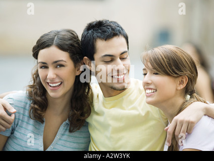 Teen boy con bracci intorno a due amici di sesso femminile Foto Stock
