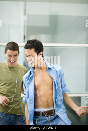 Teen maschi ascoltando gli auricolari, suonare la chitarra di aria Foto Stock