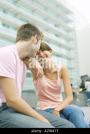 Teen giovane seduto in area urbana, sorridente ad ogni altro Foto Stock