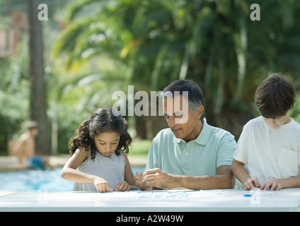 Uomo maturo mettendo insieme puzzle con i nipoti Foto Stock