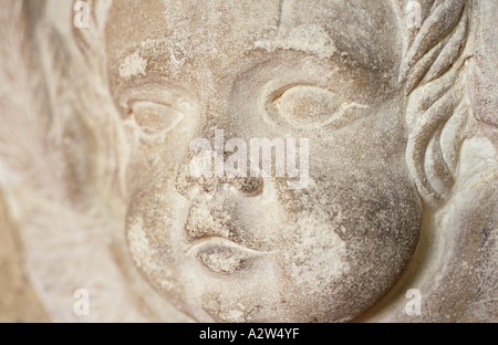 La faccia di un usurato scheggiate e sudicio pietra intagliata cherubino su un memoriale Foto Stock