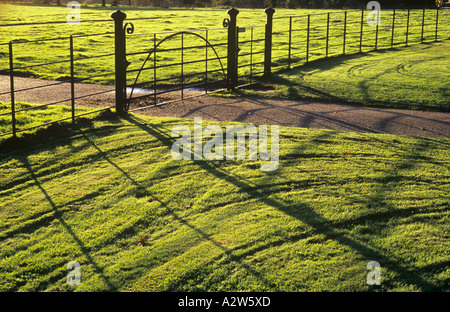 Prati con segni di recente il taglio a caldo nel tardo pomeriggio di sole autunnale con eleganti cancelli e recinzioni Foto Stock