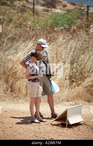 Due turisti guardando il cartello di pietra megalitico tempio di Mnajdra circa 3500BC dedicato alla dea madre della fertilità Foto Stock