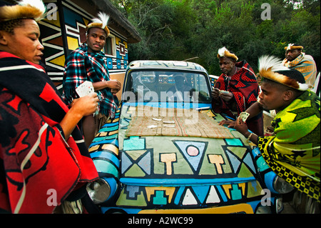Persone uomini africani carte da gioco intorno ad un vecchio modello di auto rilasciato Villaggio Culturale di Lesedi vicino a Johannesburg in Sud Africa Foto Stock