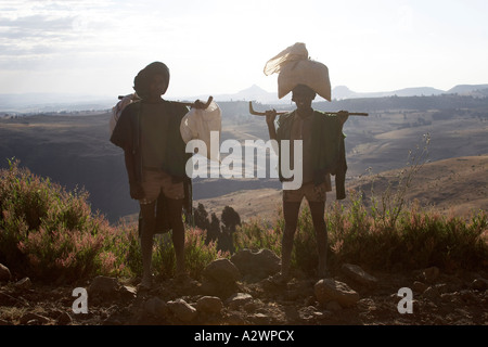 Due uomini tornare indietro a piedi dal mercato di sbarcare in Simien Mountains Etiopia Africa Foto Stock