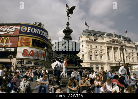 I turisti seduti sotto la statua di Eros a piccadilly circus, Londra Foto Stock